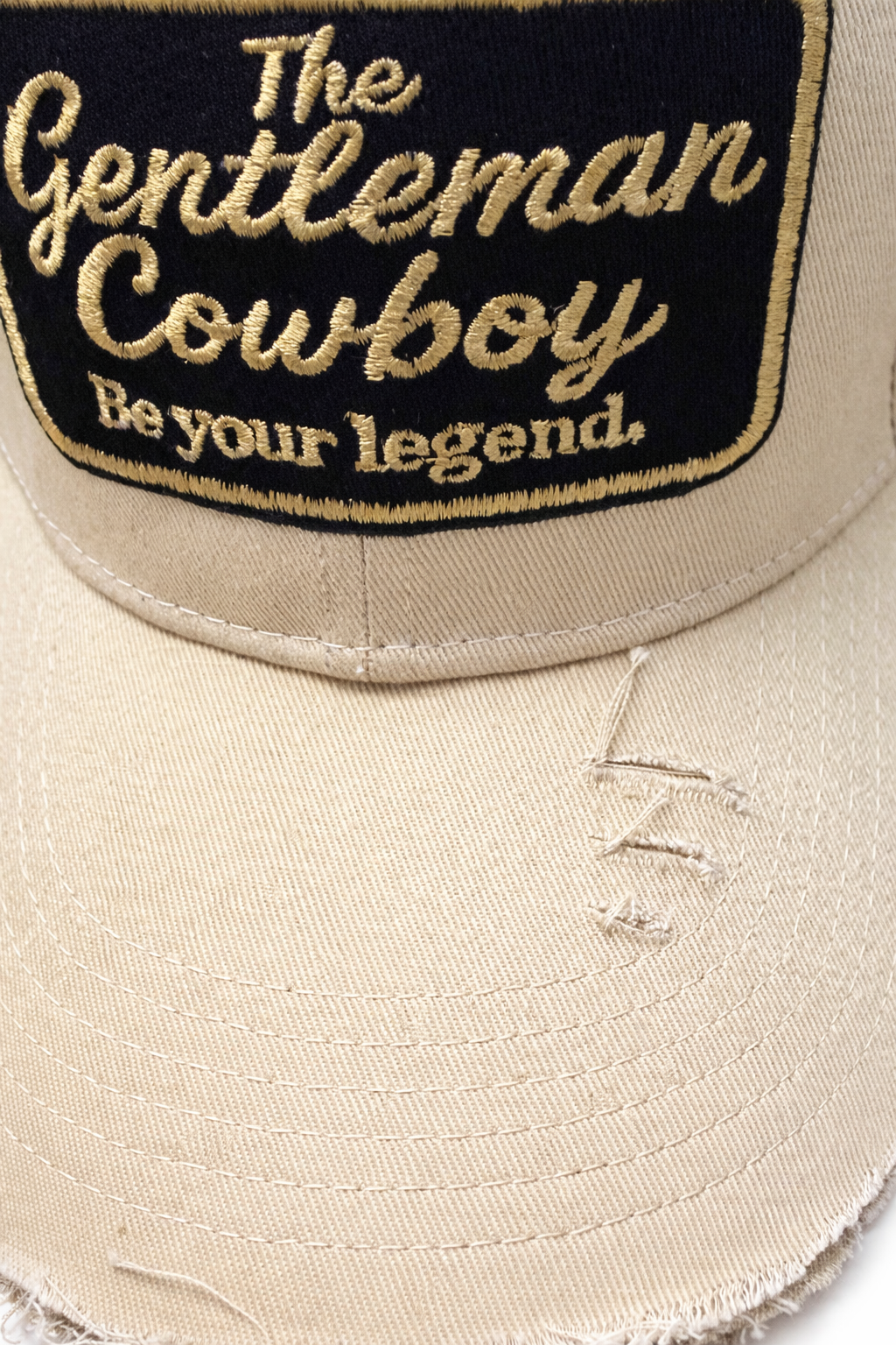 Beige cap with embroidered text 'The Gentleman Cowboy Be your legend.' on a black background